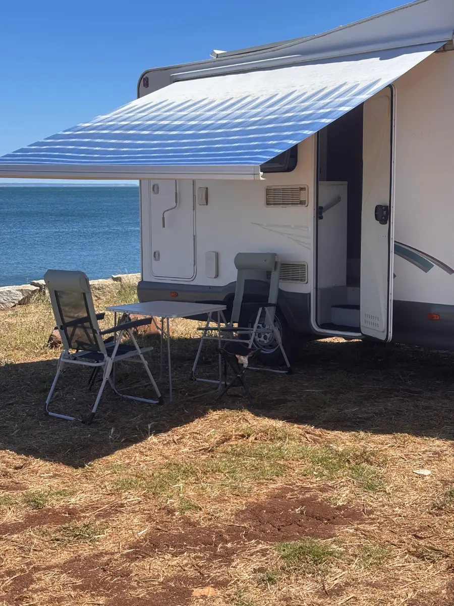Outdoor table and chairs beneath the awning by the sea