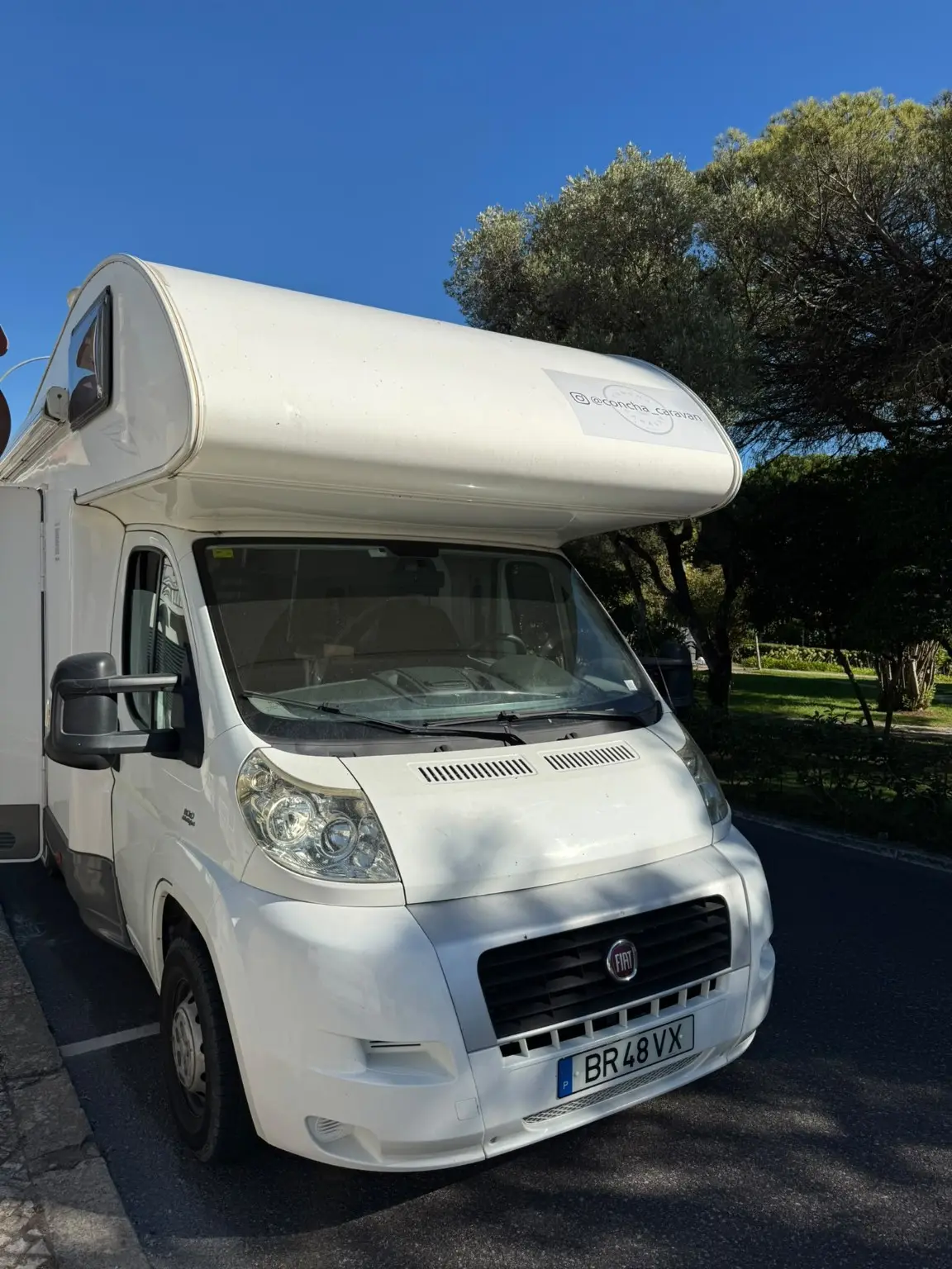 Front view of Concha Caravan beneath trees in Portugal